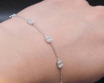 Puede incluir: Un delicado brazalete de cadena de plata con cinco pequeñas piedras preciosas transparentes de forma cuadrada.