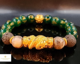 May include: A green jade bracelet with gold accents and a gold dragon charm. The bracelet also features brown lava rock and beige agate beads.