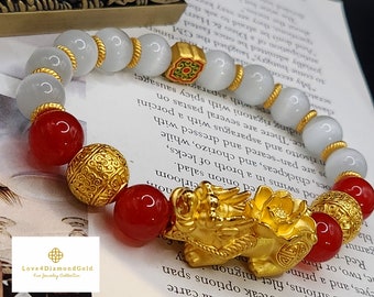 Könnte beinhalten: Ein goldenes Armband mit roten und weißen Perlen. Das Armband hat einen goldenen Drachen-Anhänger und einen goldenen Blumen-Anhänger. Das Armband ist aus Gold und hat ein traditionelles chinesisches Design.