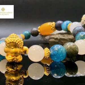 May include: A beaded bracelet featuring a gold Buddha charm and a variety of colorful gemstone beads. The bracelet includes white, blue, green, and dark-colored beads, with gold accents. The brand logo "Love4DiamondGold" is in the top left corner.