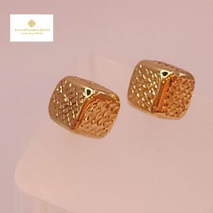 May include: A pair of gold square-shaped earrings with a textured surface. The earrings have a subtle two-tone design.
