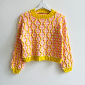 May include: A pink and yellow striped knitted sweater with a wavy pattern. The sweater has a round neckline and long sleeves.