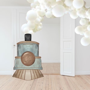 Op de afbeelding: Een blauwe en bruine speelgoedtrein met een witte ballonwolk erboven. De trein staat op een houten vloer voor een witte deur.