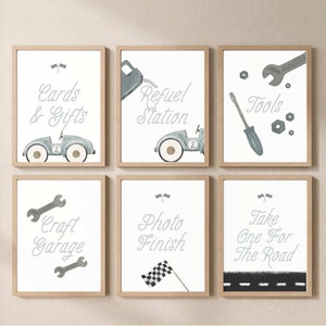 May include: Six framed prints with a racing theme. The prints feature illustrations of cars, tools, and a checkered flag. The text on the prints includes "Cards & Gifts", "Refuel Station", "Tools", "Craft Garage", "Photo Finish", and "Take One For The Road".