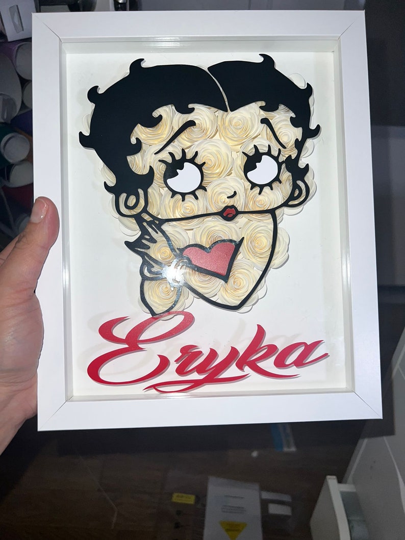 Puede incluir: Un marco blanco con una imagen en blanco y negro de un personaje de dibujos animados con un coraz&oacute;n rojo y el nombre "Eryka" en letras rojas.