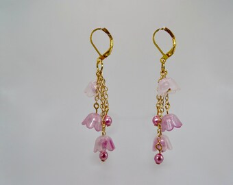Könnte beinhalten: Ein Paar Ohrringe mit pinkfarbenen Blumenanhängern und pinkfarbenen Perlen, die an goldenen Ketten hängen.