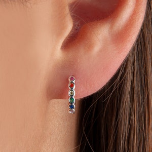 May include: A pair of rainbow hoop earrings with small, colourful gemstones. The earrings are made of silver and have a polished finish.