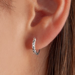 May include: Silver hoop earrings with a row of small clear cubic zirconia stones.