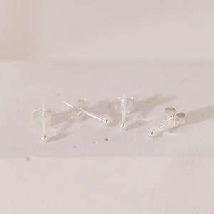 Peut inclure: Quatre boucles d'oreilles en argent avec de petites boules rondes au bout de chaque tige.