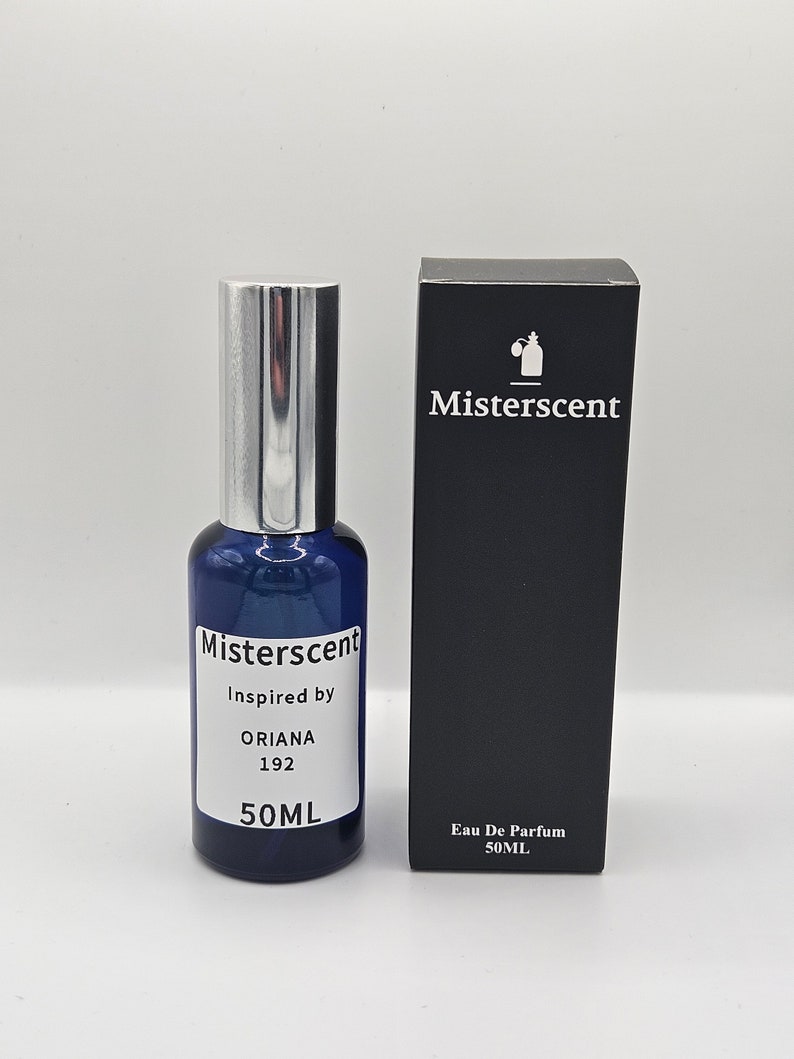 May include: A blue glass perfume bottle with a silver cap and a black box. The bottle has a white label with the text "Misterscent Inspired by ORIANA 192 50ML". The black box has the text "Misterscent Eau De Parfum 50ML".