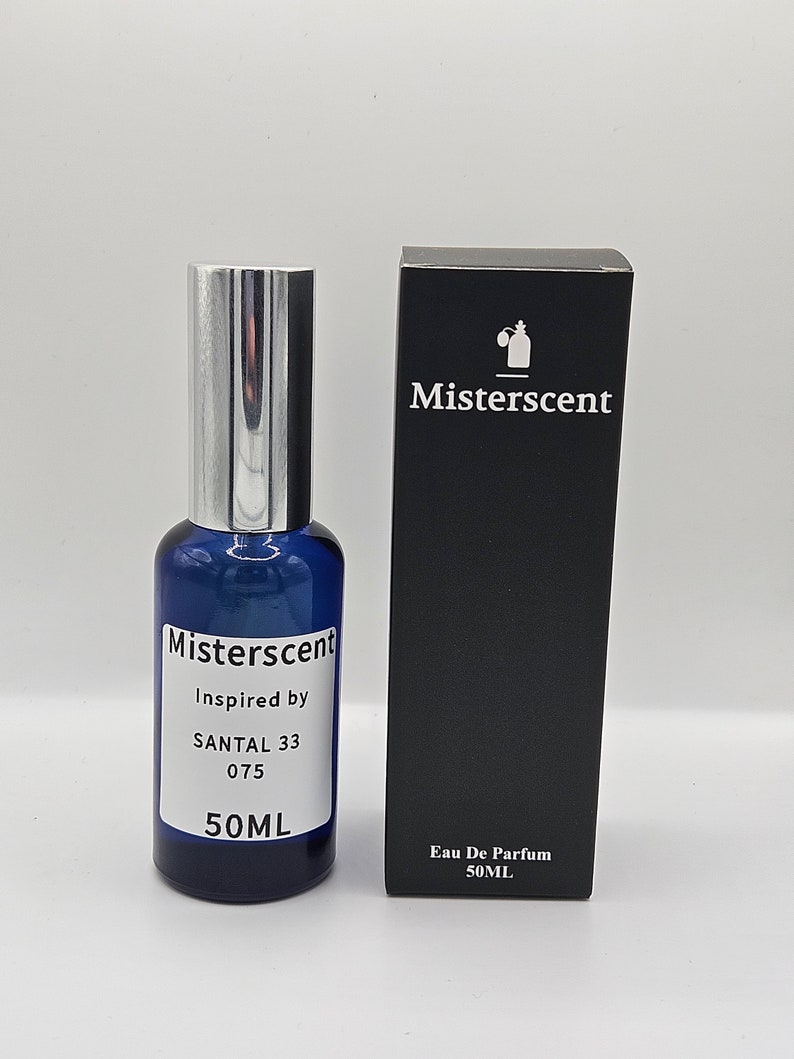 Pu&ograve; includere: Un flacone di vetro blu con un tappo argentato e un'etichetta bianca che recita "Misterscent Inspired by SANTAL 33 075 50ML". Il flacone &egrave; accanto a una scatola nera con un'etichetta bianca che recita "Misterscent Eau De Parfum 50ML".