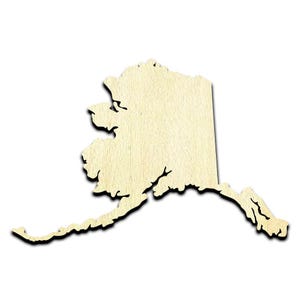 May include: A wooden cutout of the state of Alaska. The cutout is a light brown color and has a natural wood grain texture.