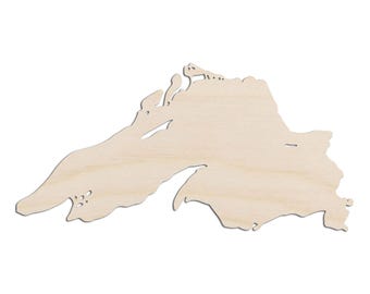 May include: A wooden cutout of Lake Superior, a large freshwater lake in North America. The cutout is made of natural wood and has a light brown color.
