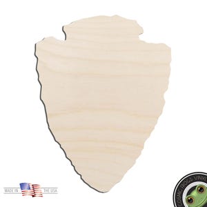 May include: A light-colored wooden arrowhead cutout. The arrowhead is made of unfinished wood and has a natural grain pattern. The image also includes the text "MADE IN THE USA" and a small American flag.