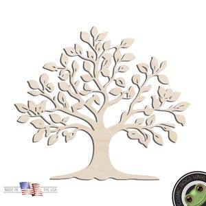 May include: A light-colored, flat wooden cutout of a tree with a wide trunk and spreading branches covered in numerous small, oval-shaped leaves. The design is symmetrical and features a smooth, natural wood grain finish throughout the entire piece.