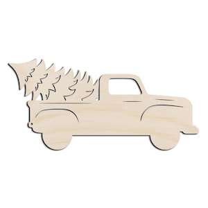 May include: A light-colored, flat wooden cutout in the shape of a vintage pickup truck carrying a large pine tree in its bed. The design features clean, laser-cut outlines of the vehicle body, wheels, and the jagged silhouette of the tree.