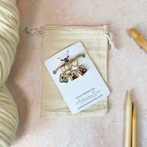 May include: Set of three gold stitch markers with colorful animal illustrations. The markers are displayed on a white card with the text "Stitch Markers by Audacious Ewe Leave the Fleece Behind audaciousewe.etsy.com".