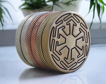 May include: A set of four round metal grinder pieces with different textures and finishes. The top piece features a geometric design.