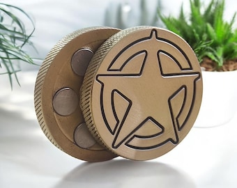 May include: A gold-toned metal fidget toy with a five-pointed star design. The toy has a spinning mechanism and is made of two pieces that fit together.