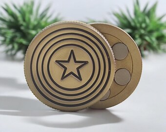 May include: A gold-colored metal fidget spinner with a star design and concentric circles. The spinner has three magnets on the back side.
