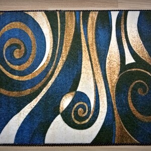 Peut inclure: Tapis rectangulaire avec un motif abstrait tourbillonnant dans les tons de bleu, or, blanc et vert. Le tapis a une bordure marron fonc&eacute; et un motif de lignes courbes et de spirales. Id&eacute;al pour une utilisation en int&eacute;rieur.