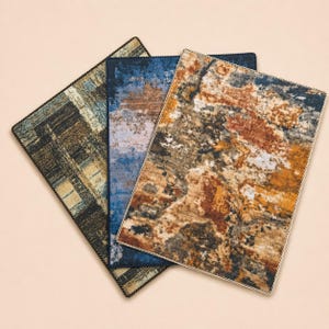 May include: Three rectangular rugs with abstract designs. One rug features a brown and tan plaid pattern, another has a blue and brown mottled design, and the third has a mix of brown, orange, and black colors. Each rug has a dark border.