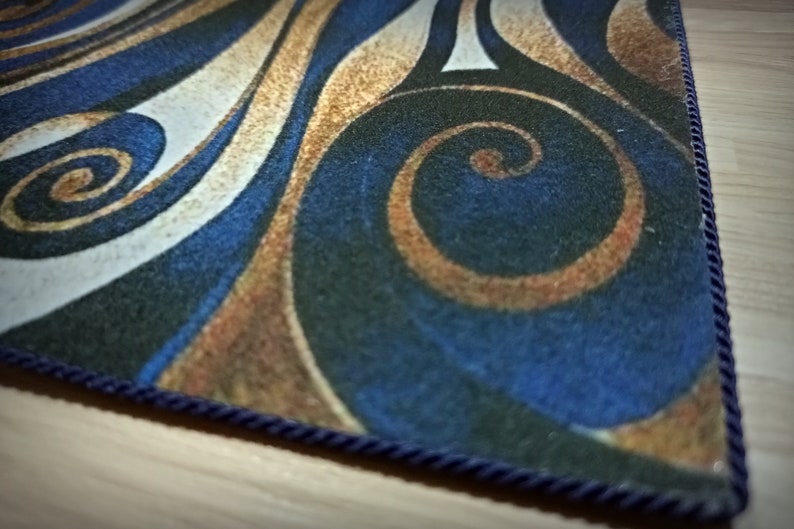 Peut inclure: Un tapis rectangulaire avec un motif tourbillonnant dans les tons de bleu, or, blanc et noir. Le tapis a une bordure en corde bleu fonc&eacute;. Le design pr&eacute;sente des lignes courbes et des formes en spirale.