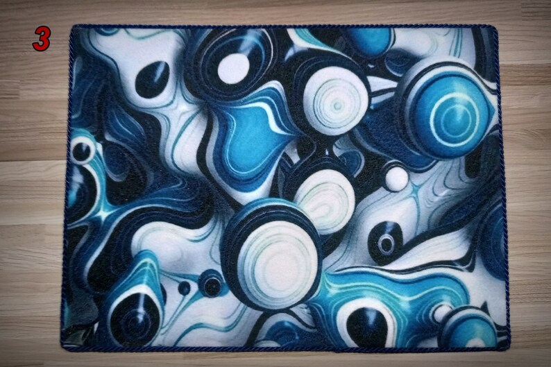 Peut inclure: Tapis rectangulaire avec un motif abstrait bleu et blanc pr&eacute;sentant des motifs tourbillonnants et des formes sph&eacute;riques. Le tapis a une bordure en corde bleu fonc&eacute; et le chiffre "3" dans le coin sup&eacute;rieur gauche.