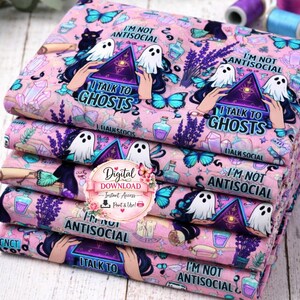 Puede incluir: Una pila de tela rosa con un patrón repetido con fantasmas, mariposas y el texto "I'm Not Antisocial" y "I Talk to Ghosts". La tela también incluye ilustraciones de cristales, botellas de pociones y lavanda. Se ve un logotipo de descarga digital.
