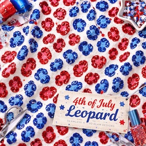 Könnte beinhalten: Weißer Stoff mit einem Leopardenmuster aus rotem und blauem Glitzer. Das Bild enthält ein Etikett mit der Aufschrift "4th of July Leopard". Schere, Nagellack und Glitzerrollen sind ebenfalls zu sehen.