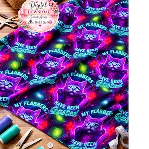 May include: A vibrant fabric featuring a repeating pattern of purple cats with the text "HAVE BEEN MY FLABBERS Gasted" against a cosmic background. Sewing supplies, including thread spools, scissors, and buttons, are arranged around the fabric.