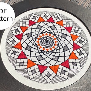 May include: A black and white geometric embroidery design with orange and red accents. The design is framed in a dark wood frame. The text "PDF pattern" is visible in the upper left corner of the image.