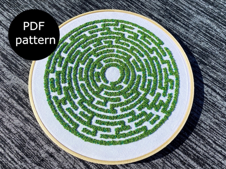May include: A white embroidery hoop with a green and blue embroidered maze pattern. The text "PDF pattern" is in black text on a black circle.