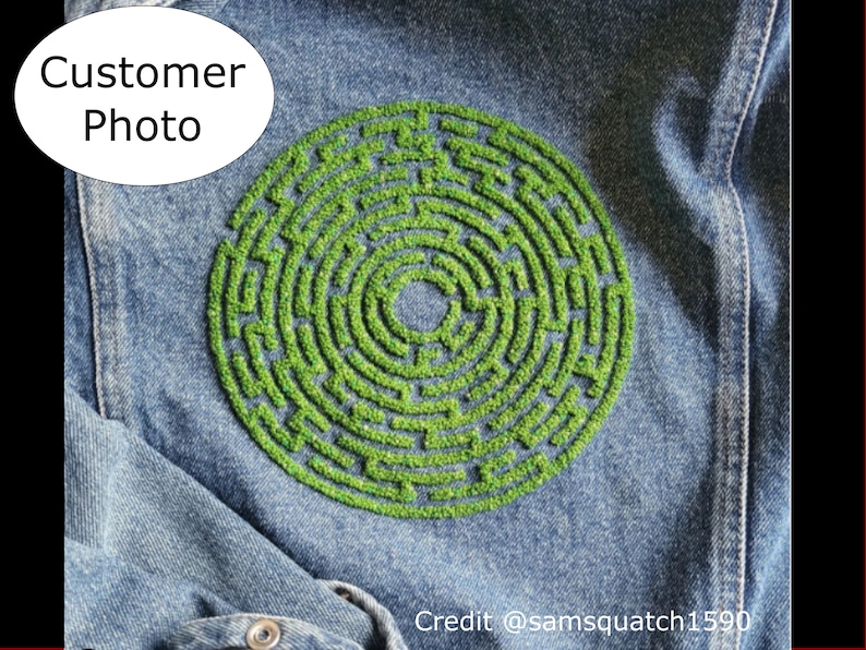 May include: A denim jacket with a green embroidered circular maze design. The maze is made of small green stitches that create a raised effect.