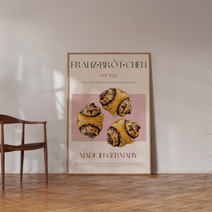 May include: A poster with a pink background featuring the text "FRANZ-BR&Ouml;T-CHEN" and "MADE IN GERMANY". The poster also features three pastry rolls with a brown and white swirl design.