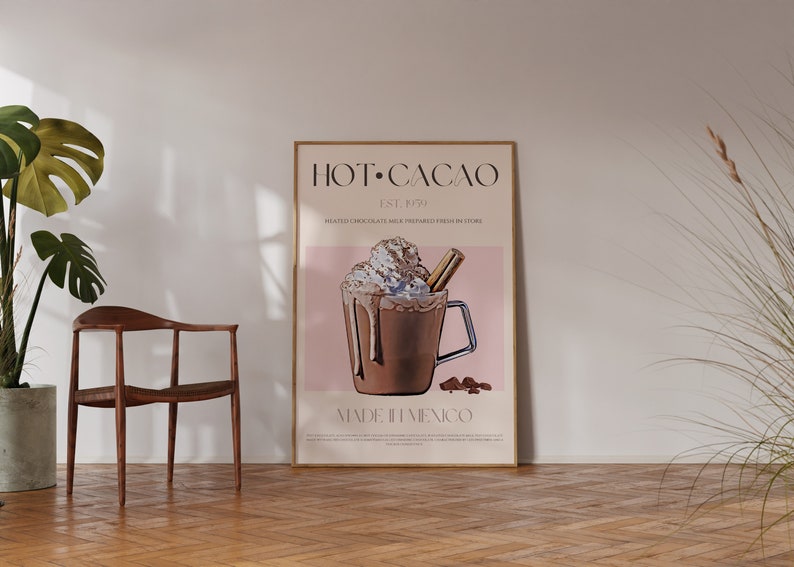 May include: A framed poster with a pink background and a graphic of a hot chocolate drink with whipped cream and a cinnamon stick. The text on the poster reads "HOT CACAO EST. 1991" and "MADE IN MEXICO".
