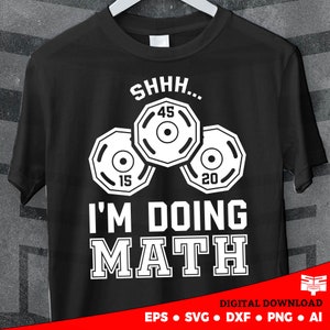 以下が含まれることがあります： 白いウェイトプレートと「SHHH... I'M DOING MATH」というテキストの白いグラフィックが描かれた黒いTシャツ。