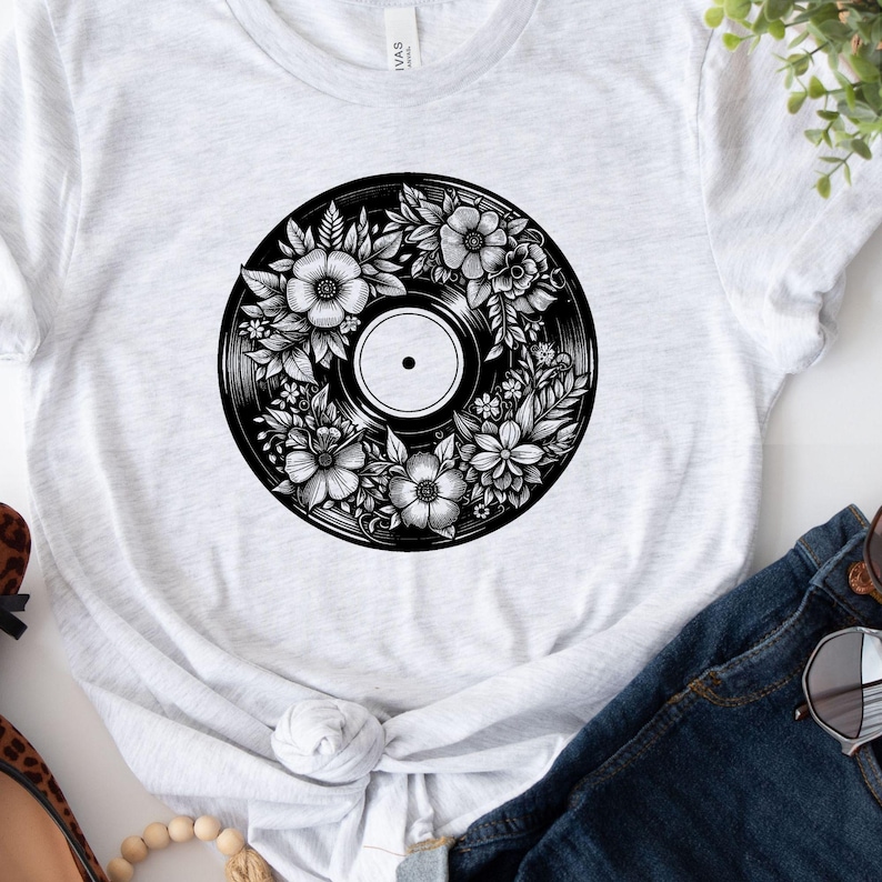 May include: A white t-shirt with a black and white graphic of a vinyl record with floral designs.