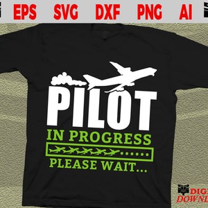 以下が含まれることがあります： 白い飛行機のグラフィックと緑色のテキスト「パイロット進行中、お待ちください...」が書かれた黒いTシャツです。