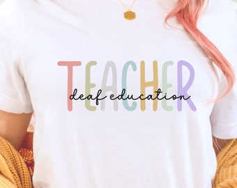 May include: A white t-shirt with the text "TEACHER deaf education" in colorful letters. The letters are in different shades of pink, yellow, green, blue, and purple.