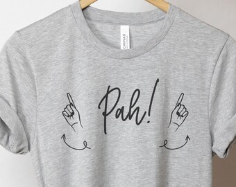 May include: Gray t-shirt with black text that says "Pah!" with two pointing hands and arrows on either side.