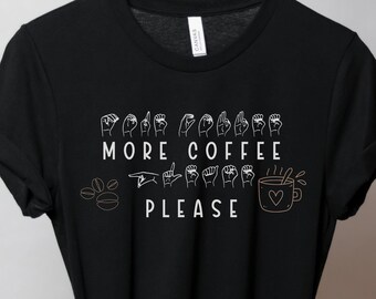 May include: Black t-shirt with white text that says "More Coffee Please" in American Sign Language. The text includes a coffee cup with a heart and a coffee bean.