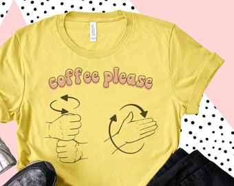May include: Yellow t-shirt with the text "coffee please" in a retro font. The text is accompanied by two hand gestures, one for "coffee" and one for "please".