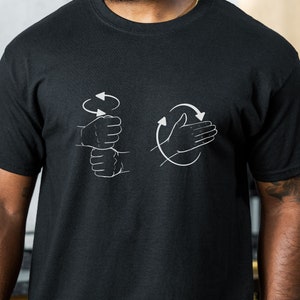 May include: A black t-shirt with white illustrations of hands demonstrating how to wash them. The illustrations show a hand with the palm facing up and a hand with the palm facing down, with arrows indicating the direction of movement.