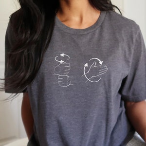 May include: A dark gray t-shirt with a white graphic of two hands demonstrating the ASL sign for "I love you".