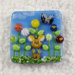Magnet aus geschmolzenem Glas - Braunes Kaninchen im Wildblumengarten mit grauem und blauem Schmetterling