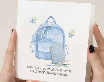 May include: A white card with a watercolor illustration of a blue backpack, notebook, and pencils. The name "Oliver" is written on the backpack. Text at the bottom reads "Good luck on your first day at Millbrook Junior School."