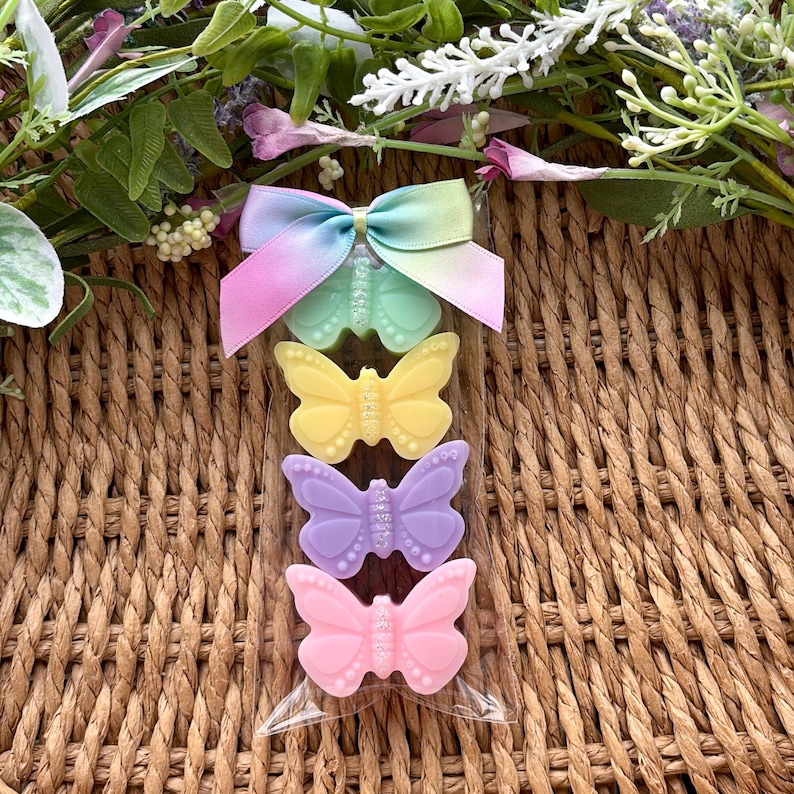Puede incluir: Una bolsa de celof&aacute;n transparente contiene cuatro accesorios con forma de mariposa. La mariposa superior es de color verde menta con un lazo de cinta arco&iacute;ris. Las otras mariposas son amarillas, lavanda y rosas. Las mariposas tienen detalles de purpurina.