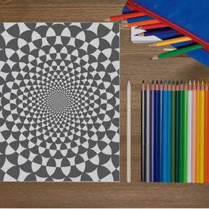 May include: A black and white coloring page with a spiral pattern of circles and triangles. The page is surrounded by a wooden table and a pencil case with colored pencils.