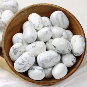 May include: A bowl filled with white howlite tumbled stones. The stones are smooth and have a white and gray marbled pattern.